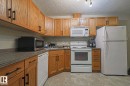 Kitchen featuring wood-finish cabinetry with black hardware, laminate countertops, and resilient flooring - 119 309 Clareview Station Drive, Edmonton, AB 