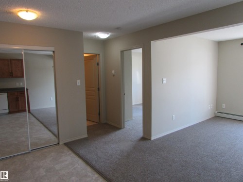 Living space featuring neutral wall paint, grey carpeting, flush mount lighting, and a mirrored closet door - 119 309 Clareview Station Drive, Edmonton, AB 