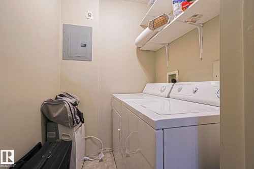 Dedicated laundry area featuring a washer and dryer, built-in shelving, and light-toned wall paint - 119 309 Clareview Station Drive, Edmonton, AB 