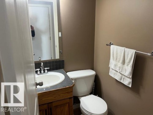 Vanity with an integrated sink, dark countertop, and tiled backsplash - 16-1033 Youville Dr. West Nw, Edmonton, AB - Indoor Photo Showing Bathroom