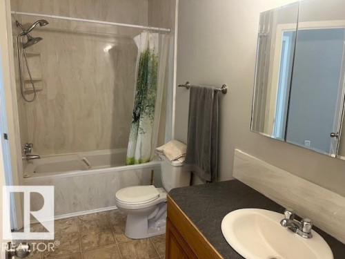 Bathroom featuring a full tub/shower combination with wall-mounted showerhead, a vanity with an integrated sink, and a mirrored medicine cabinet - 16-1033 Youville Dr. West Nw, Edmonton, AB - Indoor Photo Showing Bathroom