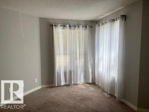 Corner windows with white sheer curtains and dark curtain rods - 16-1033 Youville Dr. West Nw, Edmonton, AB - Indoor