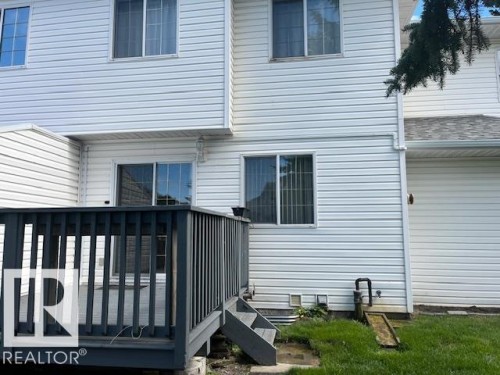 Spacious wood deck with dark-stained railing, offering direct access to the interior via a sliding glass door - 16-1033 Youville Dr. West Nw, Edmonton, AB - Outdoor With Exterior