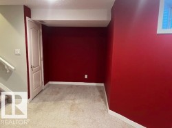 Carpeted room featuring a white paneled door, a white window frame, and white trim - 