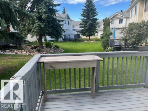 Grey-painted wood deck with a built-in folding table, overlooking a spacious lawn - 16-1033 Youville Dr. West Nw, Edmonton, AB - Outdoor With Deck Patio Veranda