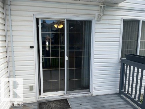 Sliding glass door with grid panes providing access to an exterior deck - 16-1033 Youville Dr. West Nw, Edmonton, AB - Outdoor With Exterior