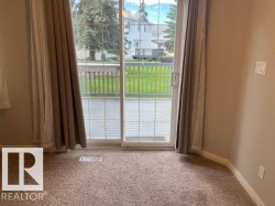 Sliding glass patio door with grid pattern, opening to a wooden deck with black railings - 