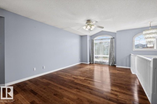 Spacious room featuring rich wood-finish flooring, vaulted ceilings, and arched windows - 946 Jordan Crescent, Edmonton, AB 