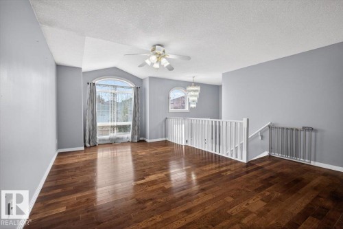 Open-concept space featuring rich wood-finish flooring, a vaulted ceiling, and an arched window - 946 Jordan Crescent, Edmonton, AB 