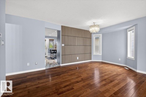 Hardwood flooring throughout the main area, featuring a decorative slatted accent wall and an ornate ceiling light fixture - 946 Jordan Crescent, Edmonton, AB 