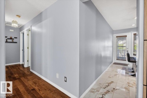 Interior hallway with wood-finish flooring transitioning to polished stone-look tile - 946 Jordan Crescent, Edmonton, AB 