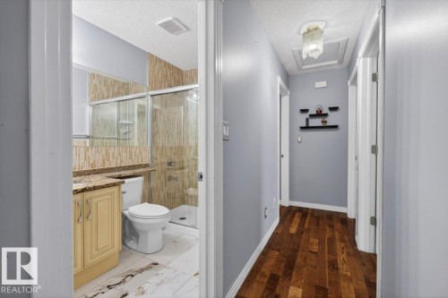 Bathroom featuring a single vanity with cabinetry, a stone-finish countertop, and a built-in mirror - 946 Jordan Crescent, Edmonton, AB 