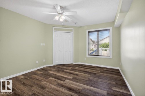 Light-filled interior space featuring wood-finish flooring, a ceiling fan with integrated lighting, window blinds for privacy, and a bi-fold closet door - 946 Jordan Crescent, Edmonton, AB 