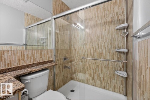 Walk-in shower with clear glass enclosure and light-toned vertical tile - 946 Jordan Crescent, Edmonton, AB 