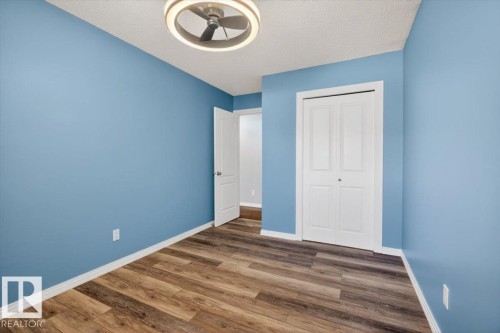 Room featuring light blue walls, wood-finish flooring, white baseboards, and a modern ceiling fan with integrated lighting - 946 Jordan Crescent, Edmonton, AB 
