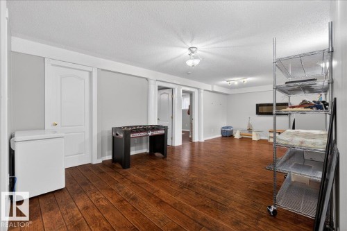 Spacious room featuring wood-finish flooring, light grey walls, and white trim - 946 Jordan Crescent, Edmonton, AB 