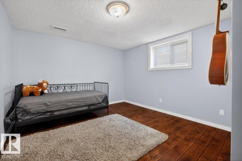 Room featuring wood-finish flooring, a window with horizontal blinds, and light-toned wall paint - 946 Jordan Crescent, Edmonton, AB 