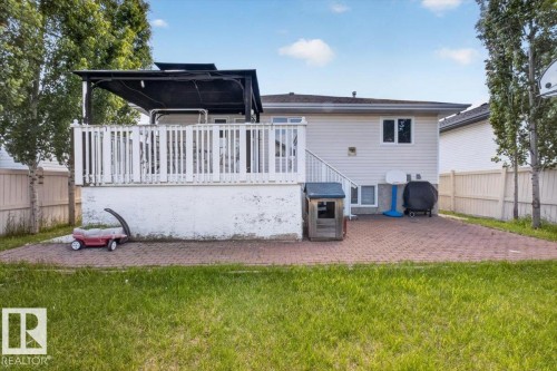 Backyard featuring a ground-level brick paver patio, a raised wooden deck with white railing, and an overhead pergola structure - 946 Jordan Crescent, Edmonton, AB 