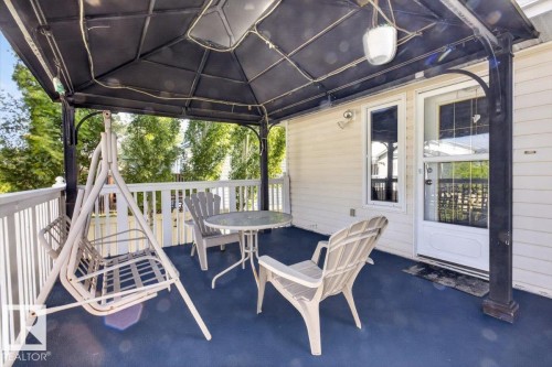 Covered outdoor porch featuring a dark blue floor, white railing, and an exterior wall with white siding - 946 Jordan Crescent, Edmonton, AB 