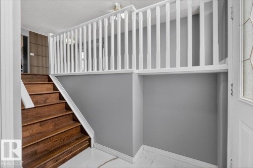 Rich wood-finish staircase with white risers and a matching white spindle railing - 946 Jordan Crescent, Edmonton, AB 