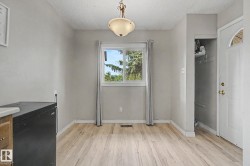 Bright interior space featuring wood-finish flooring, a central window with white trim, and light gray wall finishes - 