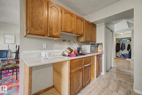 Kitchenette area featuring wood cabinetry, a sink with a chrome faucet, and a light-toned countertop - 45 2020 105 Street, Edmonton, AB 