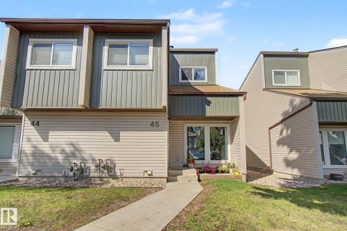 Townhome exterior featuring multi-toned siding, white-framed windows, and a concrete walkway - 45 2020 105 Street, Edmonton, AB 