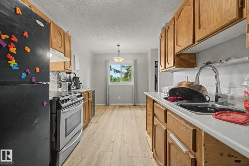 Kitchen featuring wood-finish cabinetry, stainless steel range, and a window with natural light - 45 2020 105 Street, Edmonton, AB 