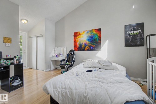 Room featuring wood-finish flooring, a vaulted ceiling, a built-in closet with sliding doors, and a glass-paneled exterior door - 45 2020 105 Street, Edmonton, AB 