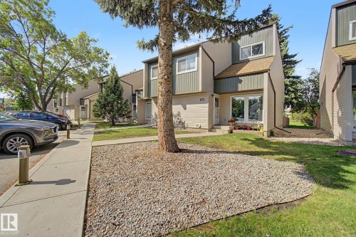 Contemporary townhome exterior featuring multi-toned siding, a distinct roofline, a prominent front entrance with large glass panels, and a concrete pathway - 45 2020 105 Street, Edmonton, AB 