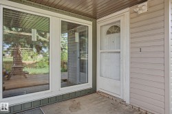 Front entry featuring a white door with an arched transom, a storm door, and horizontal siding - 