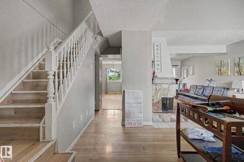 Entryway featuring wood-finish flooring, a white spindle staircase, and a stone-clad fireplace - 45 2020 105 Street, Edmonton, AB 