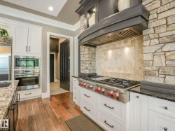Gourmet kitchen with professional-grade stainless steel range, stone surround, and integrated hood - 