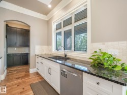 Kitchen featuring white cabinetry, dark stone countertops, and stainless steel sink - 