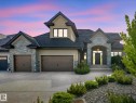Stone and stucco exterior featuring a prominent arched entry, multi-pane windows, and a black asphalt shingle roof - 2807 Wheaton Drive, Edmonton, AB 