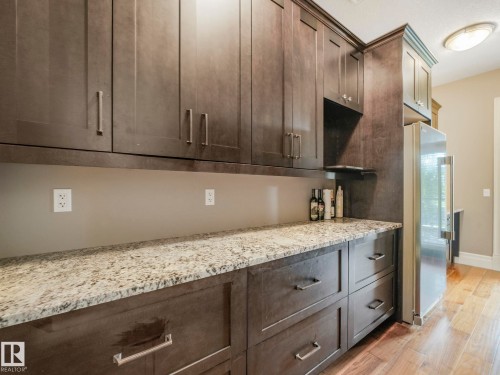 Extensive dark wood-finish cabinetry with brushed nickel hardware, light-toned speckled countertops, and wood-finish flooring - 2807 Wheaton Drive, Edmonton, AB 
