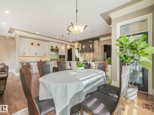 Open concept living and kitchen areas featuring wood-finish flooring, white cabinetry, a built-in beverage refrigerator, and a stone accent wall - 2807 Wheaton Drive, Edmonton, AB 