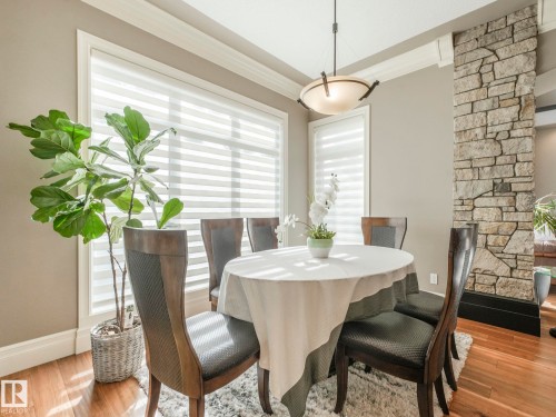 Dining area featuring wood-finish flooring, a stone-clad architectural column, and a tray ceiling with crown molding - 2807 Wheaton Drive, Edmonton, AB 