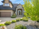 Stucco and stone facade with an arched entry, a dark wood-finish garage door, and a multi-level stone staircase - 2807 Wheaton Drive, Edmonton, AB 