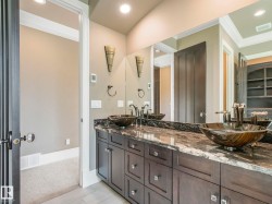 Dual vessel sinks with dark bronze fixtures, set on a dark granite countertop with white veining - 