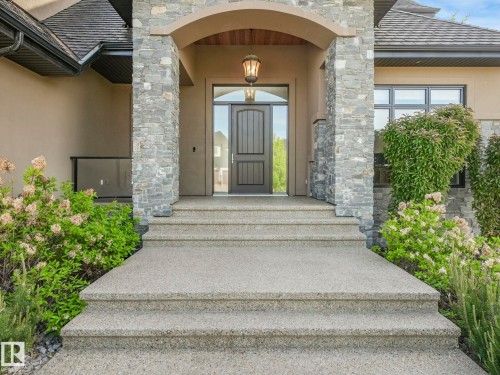 Stately entrance featuring a dark paneled door with sidelight, stone veneer columns, and an arched portico - 2807 Wheaton Drive, Edmonton, AB 