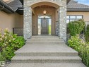 Stately entrance featuring a dark paneled door with sidelight, stone veneer columns, and an arched portico - 2807 Wheaton Drive, Edmonton, AB 