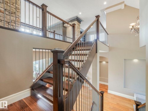 Grand staircase featuring wood-finish treads and risers, dark wood newel posts, and metal balusters - 2807 Wheaton Drive, Edmonton, AB 