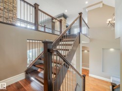 Grand staircase featuring wood-finish treads and risers, dark wood newel posts, and metal balusters - 