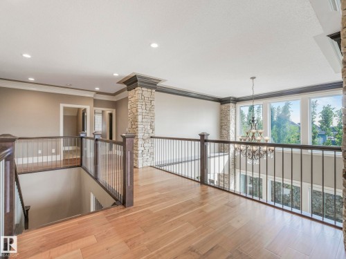Upper-level landing featuring wood-finish flooring, stone-clad architectural pillars, recessed lighting, and a wrought iron and wood banister - 2807 Wheaton Drive, Edmonton, AB 