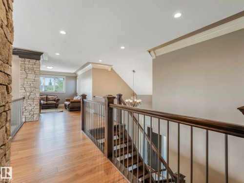Upper-level landing featuring wood-finish flooring, recessed lighting, and a stone-clad pillar - 2807 Wheaton Drive, Edmonton, AB 
