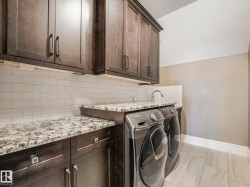 Utility area featuring dark wood-finish cabinetry, speckled countertops, a subway tile backsplash, and light-toned tile flooring - 