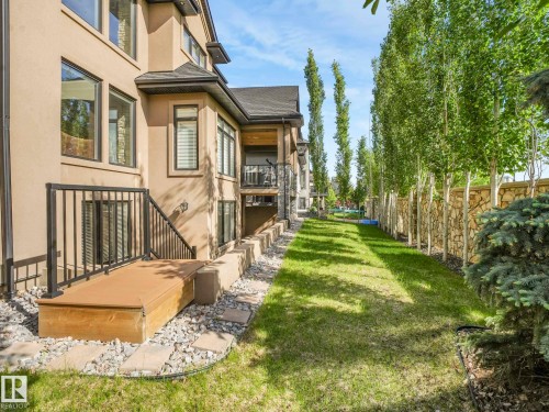 Expansive grassy side yard featuring a stone accent wall and mature trees - 2807 Wheaton Drive, Edmonton, AB 
