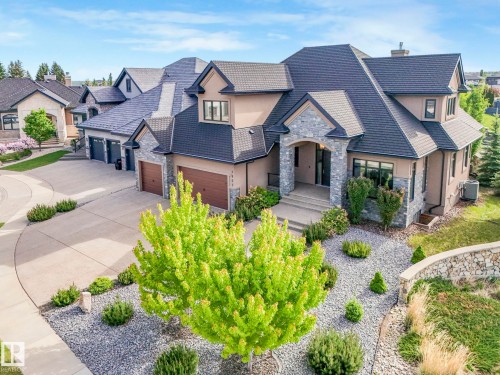 Stately residence featuring a multi-gabled roofline, stone and stucco exterior, arched front entry, and a multi-car garage with wood-finish doors - 2807 Wheaton Drive, Edmonton, AB 