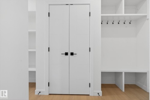 White double doors with black hardware, flanked by built-in shelving units - 105 Wyatt Ridge, Fort Saskatchewan, AB 